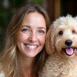 Laura Evans, puppy trainer, smiling with Labradoodle