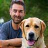 Man with dog at park, both smiling at camera